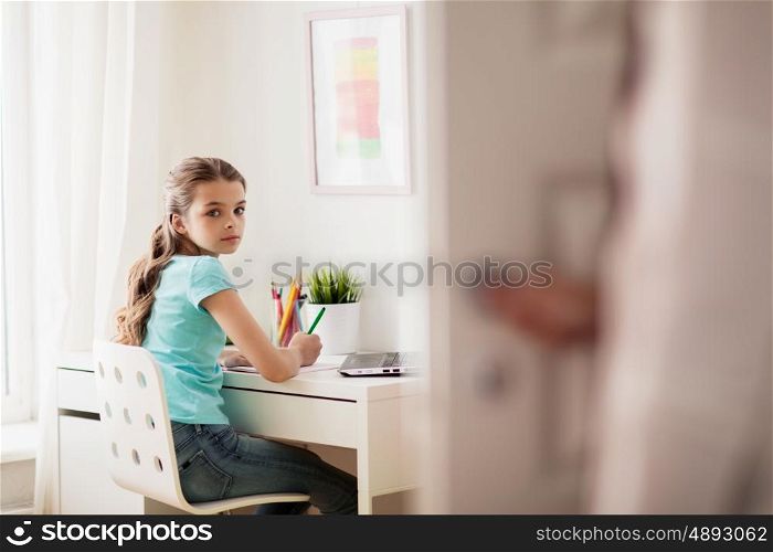 people, children, education and learning concept - girl doing homework at home and mother opens door in her room