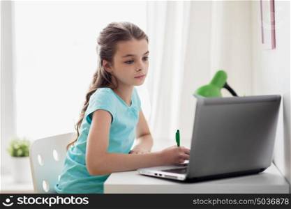 people, children, education and learning concept - girl with laptop computer writing to notebook at home. girl with laptop writing to notebook at home