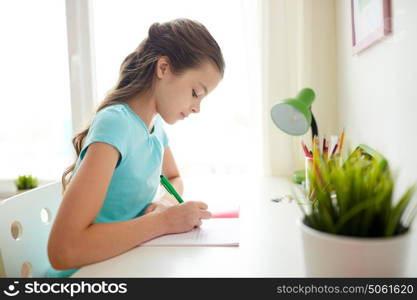 people, children, education and learning concept - girl writing to notebook at home. girl writing to notebook at home
