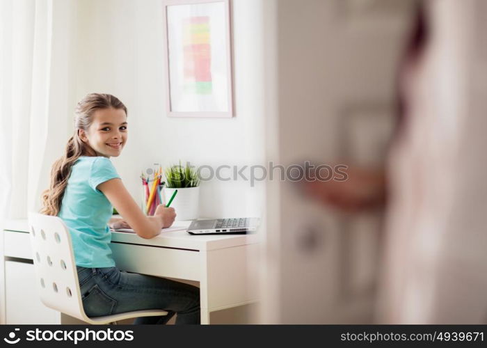 people, children, education and learning concept - happy doing homework at home and mother opens door in her room. girl with laptop writing to notebook at home