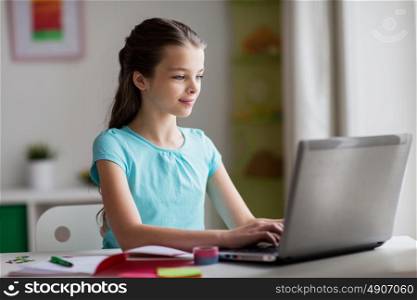 people, children, education and learning concept - happy girl typing on laptop at home. happy girl typing on laptop at home