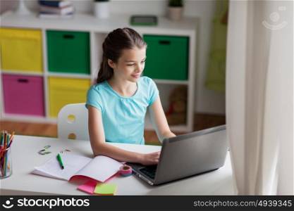 people, children, education and learning concept - happy girl typing on laptop at home. happy girl typing on laptop at home