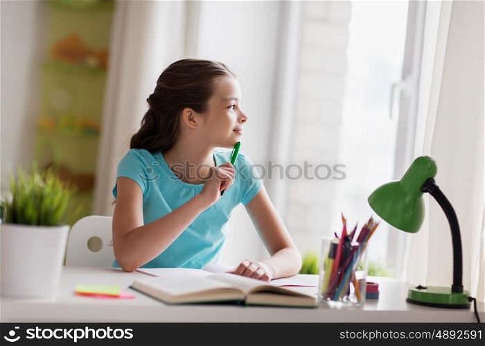 people, children, education and learning concept - happy girl with book and notebook looking through window at home