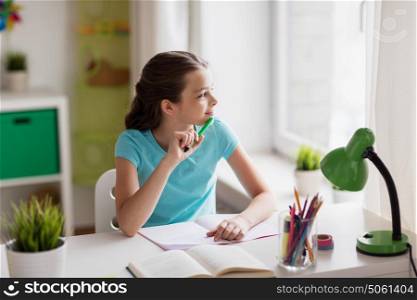 people, children, education and learning concept - happy girl with book and notebook looking through window at home. happy girl with book writing to notebook at home