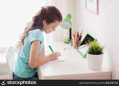 people, children, education and learning concept - happy girl with tablet pc computer writing to notebook at home. girl with tablet pc writing to notebook at home