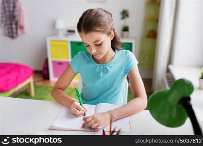 people, children, education and learning concept - happy girl writing to notebook at home. happy girl writing to notebook at home