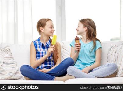 people, children, friends and friendship concept - happy little girls eating ice-cream at home