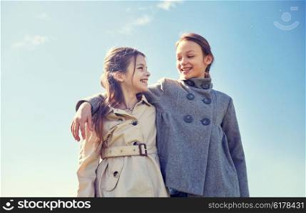 people, children, friends and friendship concept - happy little girls hugging and talking outdoors
