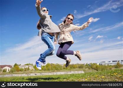 people, children, friends and friendship concept - happy little girls jumping high outdoors