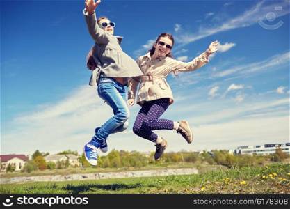 people, children, friends and friendship concept - happy little girls jumping high outdoors