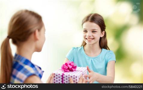 people, children, holidays, friends and friendship concept - happy little girls with birthday present over green background
