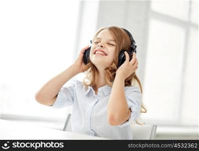 people, children, leisure, technology and music concept - smiling little girl with headphones at home. smiling little girl with headphones at home