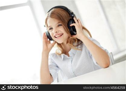 people, children, leisure, technology and music concept - smiling little girl with headphones at home