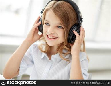 people, children, leisure, technology and music concept - smiling little girl with headphones at home