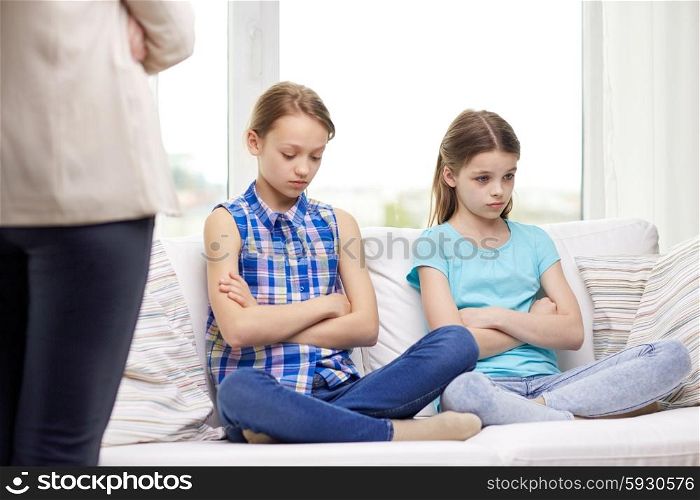 people, children, misbehavior, friends and friendship concept - upset feeling guilty or displeased little girls sitting on sofa and mother at home