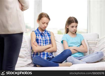 people, children, misbehavior, friends and friendship concept - upset feeling guilty or displeased little girls sitting on sofa and mother at home