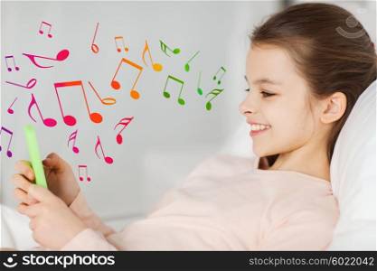 people, children, music and technology concept - happy smiling girl lying awake with smartphone in bed at home over musical notes