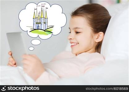 people, children, rest and technology concept - happy smiling girl lying awake with tablet pc computer in bed at home with doodle of fairy castle in cloud