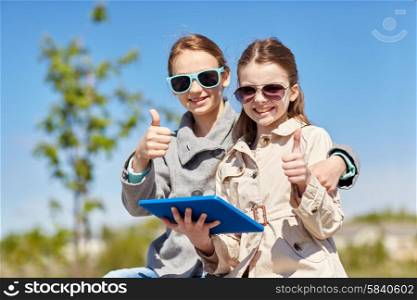 people, children, technology, friends and friendship concept - happy little girls in sunglasses with tablet pc computer showing thumbs up outdoors