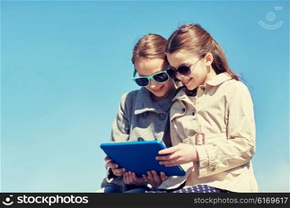 people, children, technology, friends and friendship concept - happy little girls in sunglasses with tablet pc computer outdoors