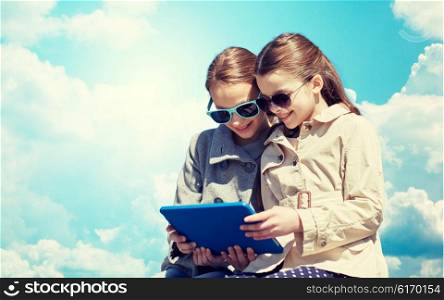 people, children, technology, friends and friendship concept - happy little girls in sunglasses with tablet pc computer over blue sky and clouds background