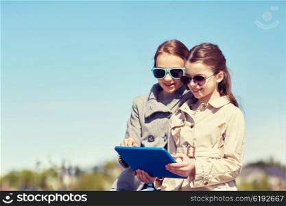 people, children, technology, friends and friendship concept - happy little girls in sunglasses with tablet pc computer outdoors
