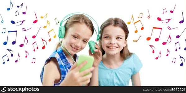 people, children, technology, friends and friendship concept - happy little girls with smartphone and earphones sitting on sofa and listening to music