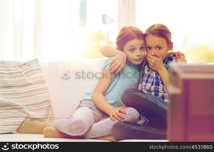 people, children, television, friends and friendship concept - two scared little girls watching horror on tv at home