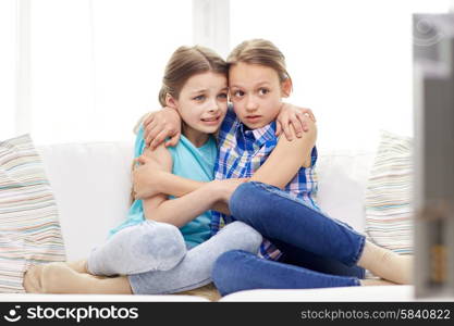 people, children, television, friends and friendship concept - two scared little girls watching horror on tv at home