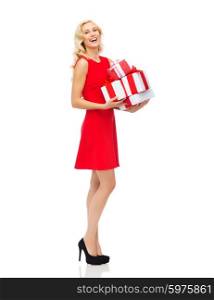 people, christmas, birthday and holidays concept - happy young woman in red dress holding gift boxes