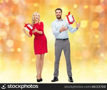 people, christmas, birthday, couple and holidays concept - happy young man and woman with gift boxes over lights background