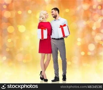 people, christmas, birthday, couple and holidays concept - happy young man and woman with gift boxes over lights background