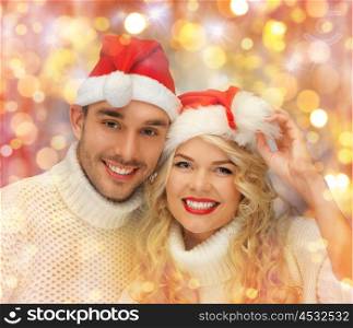people, christmas, holidays and new year concept - happy family couple in sweaters and santa hats over holidays lights and snow background