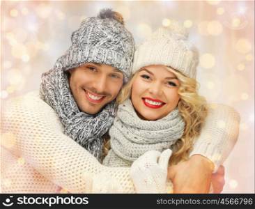 people, christmas, holidays and new year concept - happy family couple in winter clothes hugging over holidays lights background. happy family couple in winter clothes hugging