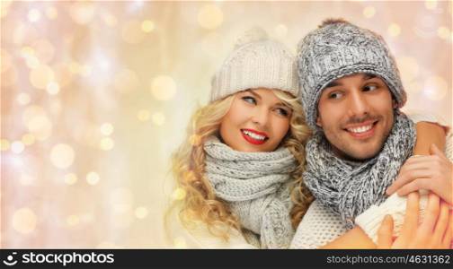 people, christmas, holidays and new year concept - happy family couple in winter clothes hugging over holidays lights background