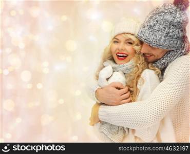 people, christmas, holidays and new year concept - happy family couple in winter clothes hugging over holidays lights background