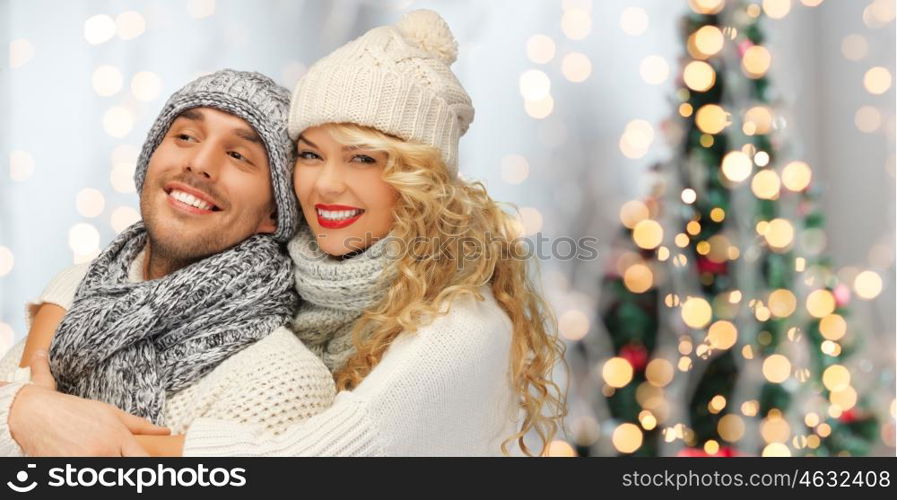 people, christmas, holidays and new year concept - happy family couple in winter clothes hugging over lights background