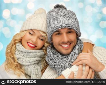 people, christmas, holidays and new year concept - happy family couple in winter clothes hugging over blue lights background