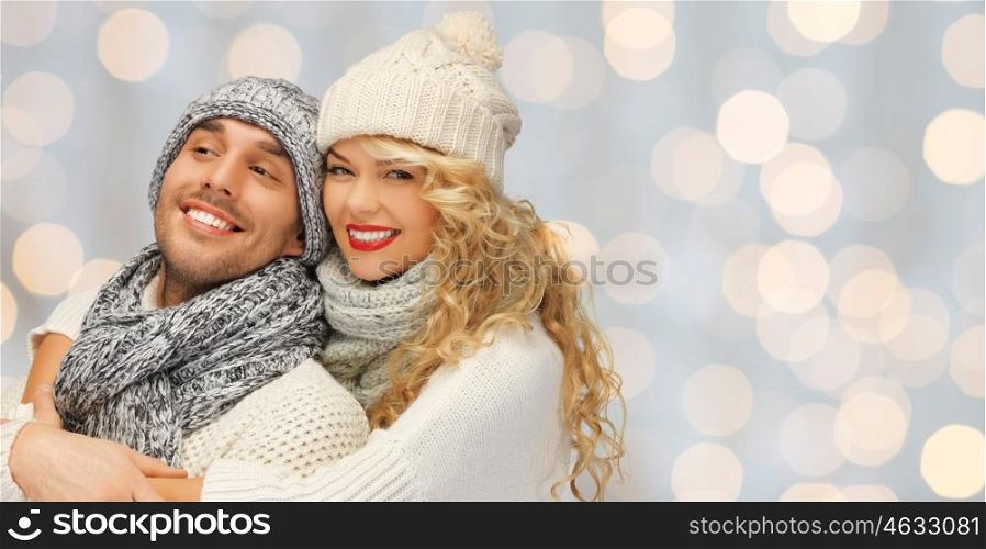 people, christmas, holidays and new year concept - happy family couple in winter clothes hugging over lights background