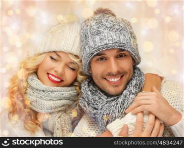 people, christmas, holidays and new year concept - happy family couple in winter clothes hugging over holidays lights background. happy family couple in winter clothes hugging
