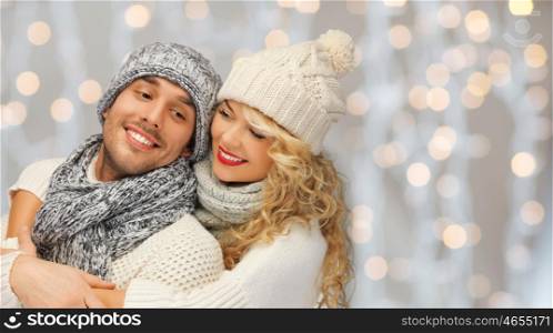 people, christmas, holidays and new year concept - happy family couple in winter clothes hugging over lights background