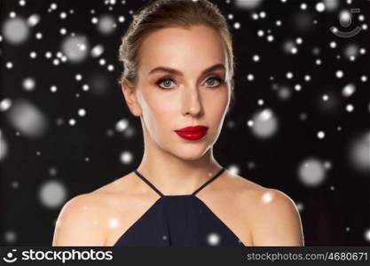 people, christmas, holidays, luxury and fashion concept - beautiful woman with red lips over black background and snow