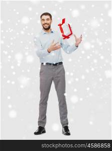 people, christmas, winter and holidays concept - happy young man playing with gift box over snow background