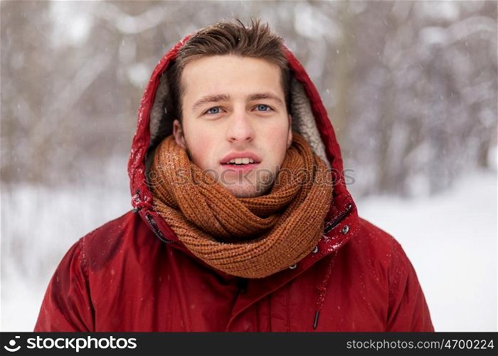 people, christmas, winter and season concept - happy man in hood and scarf outdoors