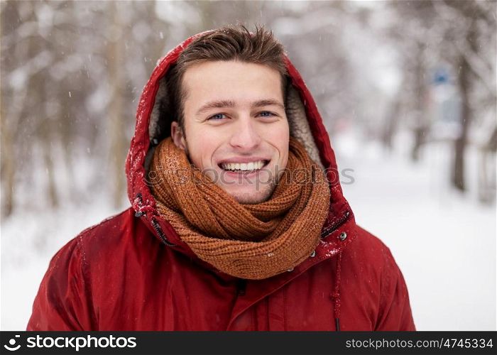 people, christmas, winter and season concept - happy smiling man in hood and scarf outdoors