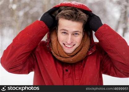 people, christmas, winter and season concept - happy smiling man in jacket and scarf wearing hood outdoors