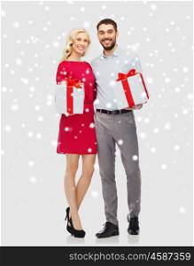 people, christmas, winter, couple and holidays concept - happy young man and woman with gift boxes over snow background