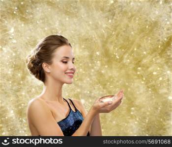 people, christmas, winter holidays and glamour concept - smiling woman in evening dress with diamond over yellow lights background