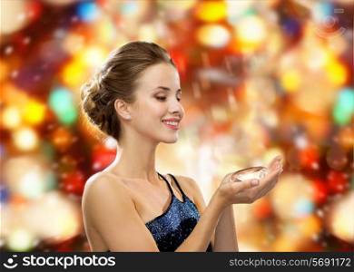people, christmas, winter holidays and glamour concept - smiling woman in evening dress with diamond over red lights background