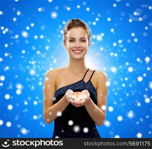 people, christmas, winter holidays and glamour concept - smiling woman in evening dress with diamond over blue snowy background